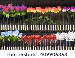 Colorful plastic roses in two rows in front of a dark grey wall; Funfair booth; Shooting gallery at the fair