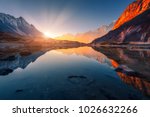 Beautiful landscape with high mountains with illuminated peaks, stones in mountain lake, reflection, blue sky and yellow sunlight in sunrise. Nepal. Amazing scene with Himalayan mountains. Himalayas
