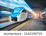 High speed train in motion on the railway station at sunset. Blue modern intercity passenger train with motion blur effect on the railway platform. Railroad in Europe. Commercial transportation