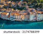 Aerial view of beautiful old houses with orange roofs at sunset in summer in Rovinj, Croatia. Top view of colorful architecture in old city and sea coast. Historical centre, buildings on the water