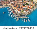 Aerial view of beautiful old houses with orange roofs, boats and yachts in dock at sunset in summer in Rovinj, Croatia. Top view of colorful architecture in old city and sea coast. Historical centre