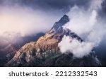 Small photo of Mountain peak in low clouds at colorful sunset in Nepal. Dramatic landscape with beautiful high rocks in fog, moody sky, sunlight, tress, grass at sunset. Nature. Himalayan mountains. Scenery