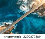 Aerial view of bridge, sea with waves and stones at sunset in Lofoten Islands, Norway. Landscape with beautiful road, transparent blue water, rocks. Top view from drone of highway in summer. Transport