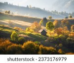 Small photo of Carpathian mountain valley with beautiful hills in haze, alone small wooden house, orange trees at sunset in autumn in Ukraine. Colorful landscape with meadows, forest, grass, sunlight in fall. Nature