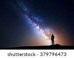 Landscape with Milky Way. Night sky with stars and silhouette of a standing happy man on the mountain.