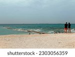 Tourists standing on the sandy beach, enjoying the view of the Road to Heaven, which is a curvy jetty and a popular IG check-in point, on a sunny summer day, in Baisha, Penghu County, Taiwan
