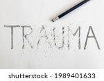 Small photo of Erasing trauma. Trauma written on white paper with a pencil, partially erased with an eraser. Symbolic for overcoming trauma or treating trauma.