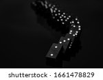 Black vintage falling dominoes on a black background, selective focus. WB photo.