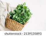 fresh organic nettles in a wicker basket on a white background. Top view. Copy space. Herbal medicine concept.