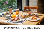 Small photo of Breakfast in luxury hotel. Table full of various food from buffet in modern resort. Morning food - fresh bakery, glasses of orange juice, eggs, cold cuts and plate with tropical fruits in restaurant