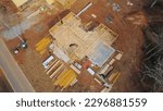 Small photo of Wooden frame beam, joist, truss, plank and building materials of residential single-family house on concrete slab foundation service road in suburban area of Flowery Branch, Georgia, USA. Aerial view