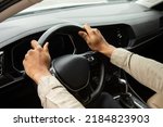 Two hands hold the steering wheel inside the car.