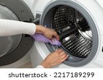 The concept of cleaning the details of a washing white machine, a stainless steel drum inside, close-up, no face
