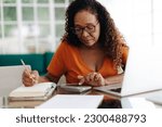 Small photo of Senior woman making calculations on her retirement annuity, reviewing her pension plan and social security benefits. Elderly black woman using her financial literacy and planning skills at home.