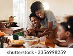 Small photo of Brazilian family having breakfast, with mom and son sharing hugs at their kitchen table. Happy black family enjoying quality time together, with fresh cheese bread rolls served on the table.