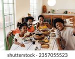 Small photo of Happy Brazilian family sitting at the table for a traditional meal, with clay pots filled with delicious dishes. They smile and pose for a selfie, creating memories in their kitchen.