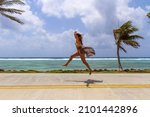 Small photo of A happy woman jumps on the street in front of the ocean in san Andres Island, Colombia