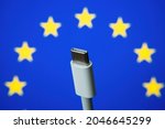 Concept for EU law to force USB-C chargers for all phones. EUROPEAN UNION flag and USBC universal charging cable. Selective focus.