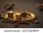 Chocolates treats, pralines, nuts, coffee beans on vintage metallic plate on dark background, copy space 