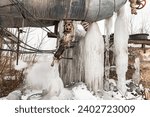 Small photo of Steam metal pipe leaks water. Pipe burst in winter. Frozen water from steam pipes in winter close up. Huge steam pipes of the central boiler plant.