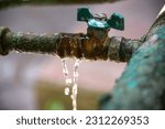 Small photo of Water leakage at the junction of the water shut-off valve and pipe. Technical problem of rusty pipes in the garden.