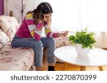 Small photo of Frustrated teen girl sitting on sofa look at negative pregnancy result test. Disappointed stressed teenager worried about unplanned pregnancy, fertility infertility, IVF, maternity concept