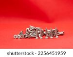 Small photo of Tapping screws made of steel on red color background, metal screw, iron screw, chrome screw, screws as a background, wood screw, concept industry. copy space for text.