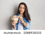 Small photo of Lovely beautiful girl is holding a large amount of cash, a lot of money from Brazil. Business, income, loan, pay, buy, wealth concept.