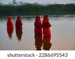 Small photo of Hindu devotee offering prayers to sun god standing in water according to hindu rituals during Chhath Puja Festival. Chath Puja rituals