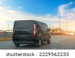 Black modern passenger charter van with a small delivery moves fast on the highway to the urban suburbs. Business distribution and logistics express service. Mini bus rides along the highway
