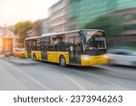 Small photo of City yellow bus rush motion blur effect through the streets of the city in the evening at sunset peak hour