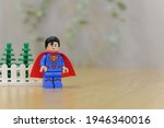 Small photo of Surabaya, Indonesia - March 19, 2021: superman happy photo with grey blur background and wood base texture. lego minifigs are made by the lego group