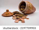 Small photo of a pile of british copper penny and two pence coins next to a glazed Spanish pottery honey jar