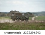 Small photo of Army Land Rover Wolf Defender with canvass back cover driving on a dirt road