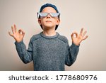 Small photo of Young little caucasian kid wearing internet meme thug life glasses over isolated background relax and smiling with eyes closed doing meditation gesture with fingers. Yoga concept.