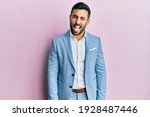 Young hispanic businessman wearing business jacket sticking tongue out happy with funny expression. emotion concept. 