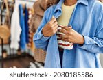 Small photo of Young latin robber woman stealing handbag at clothing store.