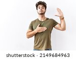 Small photo of Hispanic man standing over isolated white background swearing with hand on chest and open palm, making a loyalty promise oath