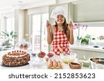 Small photo of Beautiful young brunette pastry chef woman cooking pastries at the kitchen gesturing finger crossed smiling with hope and eyes closed. luck and superstitious concept.