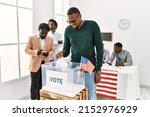 Young american voter man smiling happy putting vote in voting box at electoral center.