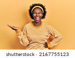 Small photo of Young african american woman presenting with open palms, holding something smiling and laughing hard out loud because funny crazy joke.