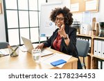 African american woman with afro hair working at the office wearing operator headset pointing fingers to camera with happy and funny face. good energy and vibes. 