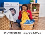 African american woman smelling towel washing clothes at laundry room
