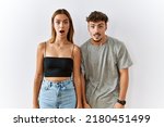 Young beautiful couple standing together over isolated background afraid and shocked with surprise and amazed expression, fear and excited face. 