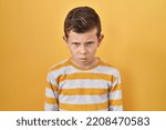 Small photo of Young caucasian kid standing over yellow background skeptic and nervous, frowning upset because of problem. negative person.