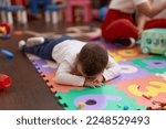 Small photo of Adorable toddler lying on floor crying at kindergarten