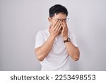 Young asian man standing over white background rubbing eyes for fatigue and headache, sleepy and tired expression. vision problem 