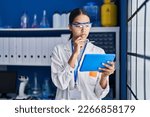 Young african american woman scientist using touchpad with doubt expression at laboratory