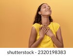 Young african american woman smiling confident with hands on heart over isolated yellow background