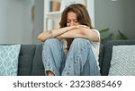 Young beautiful hispanic woman sitting on the sofa crying at home